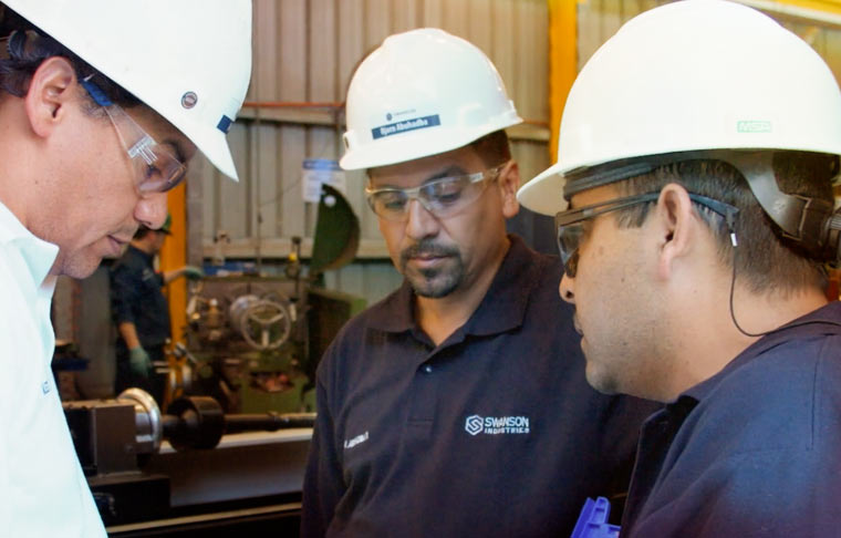 Swanson workers in hardhats having a meeting on the production floor